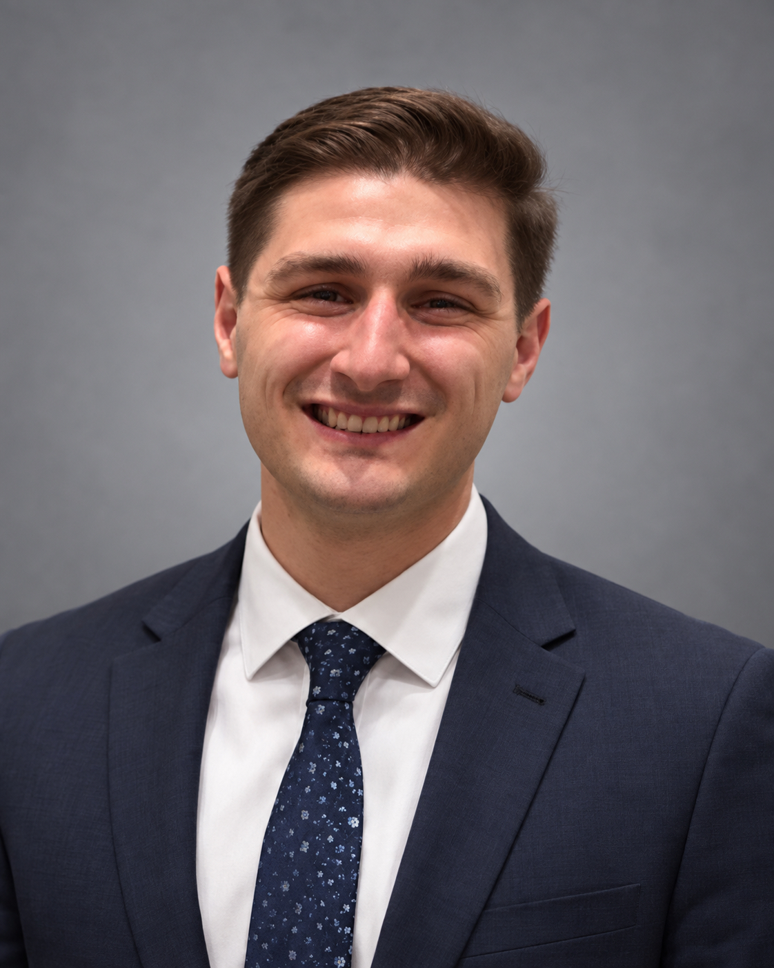 Sam Ricci smiling in a navy suit